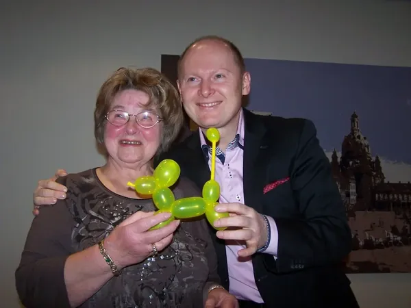 Peter Lissek mit einem Gast und einer Ballonfigur auf einer Feier